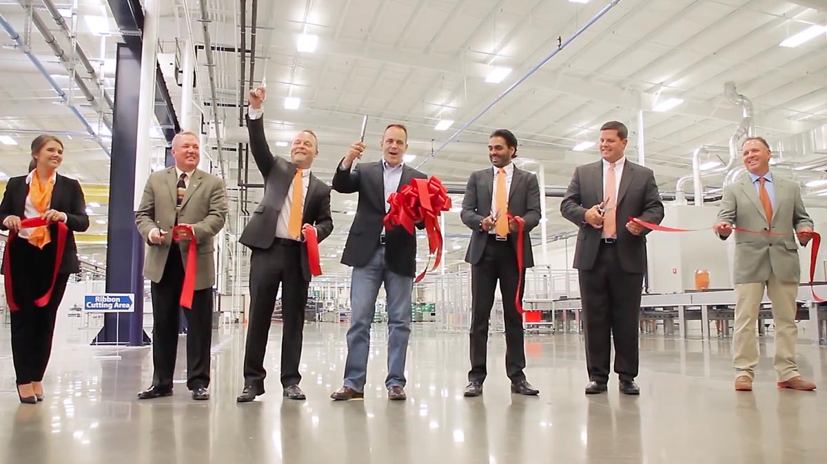 red ribbon cutting at plant opening in Russell County